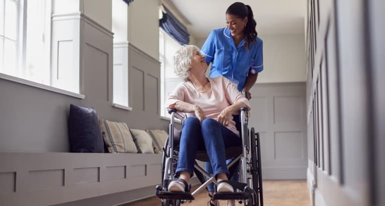Careworker wheeling elderly lady in wheelchair