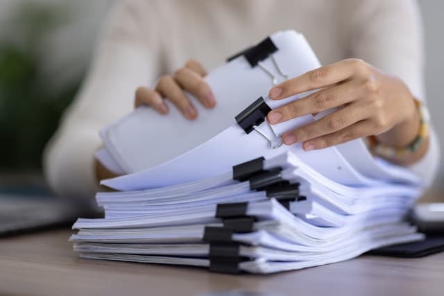 woman looking through a pile of documents 