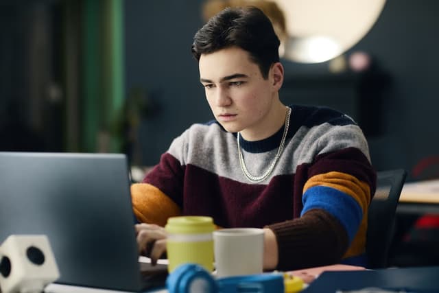 teenage boy using laptop in his room
