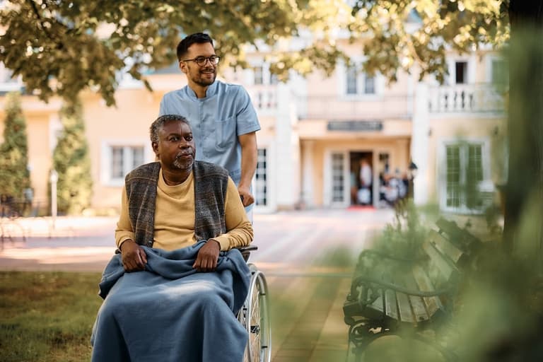 carer wheeling man in wheelchair