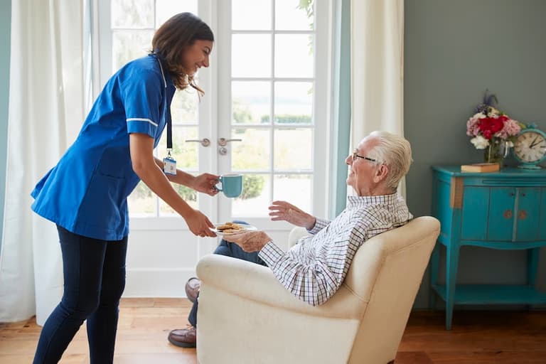 Care worker bringing elderly man a cup of tea